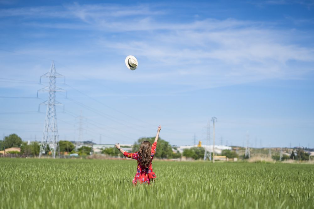 Young woman throwing up hat in field