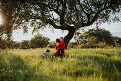 A mother embracing her child in a park in front of a tree