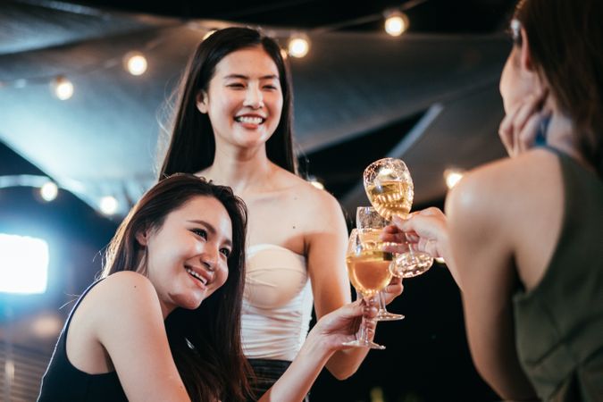 Happy female Asian friends smiling and toasting glasses of wine together