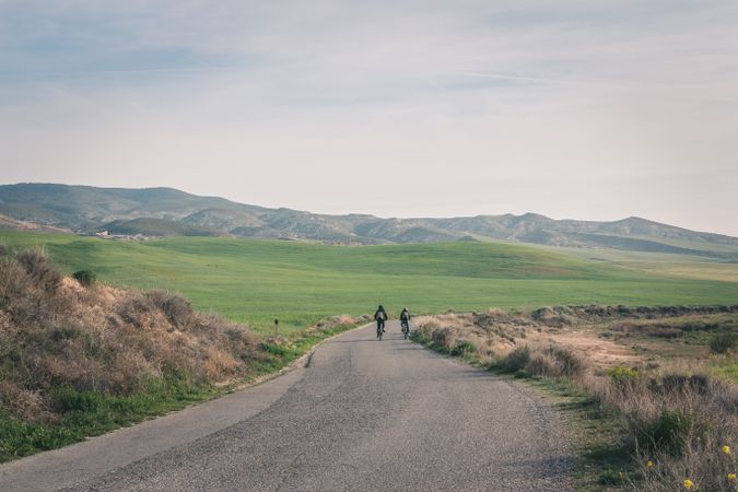 Men riding bicycles on road in desert hills