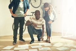 Multi-ethnic group of colleagues reviewing data and charts on paper laid on the ground