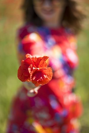 Blurred woman giving flower to camera