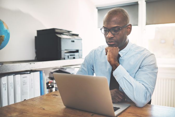 Man contemplating work on his laptop in a home office