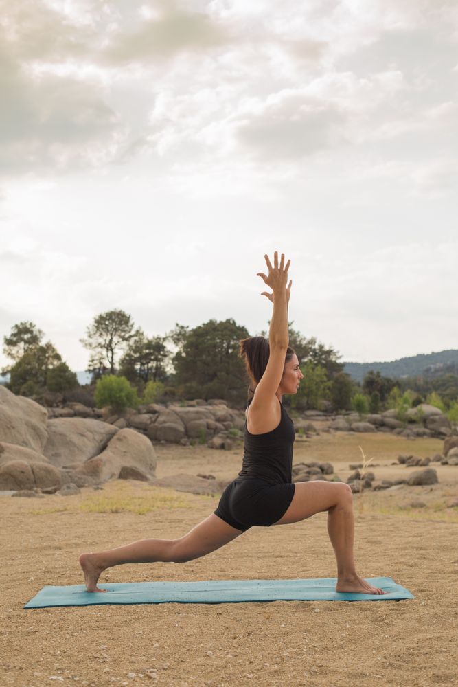Woman practicing yoga outdoors near water