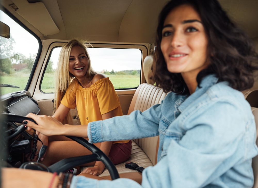 Two female friends laughing while driving a car