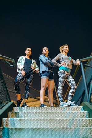 Group of female runners team standing on stairs at night ready for an evening exercise session