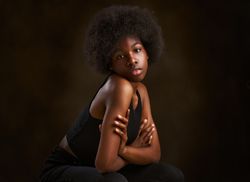 Happy young woman with afro hairstyle sitting with arms folded