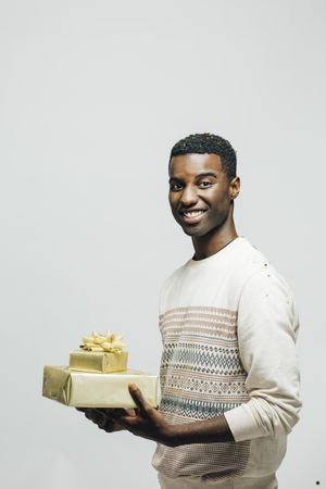 Happy Black man holding a wrapped present in a bright room