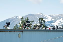 Telescopes on rooftop with mountains in background.