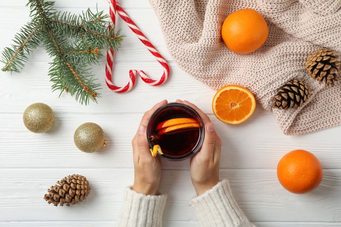 Girl holding glass with mulled wine on decorated wooden background, top view