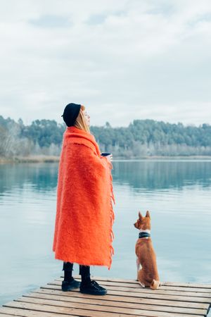 Woman calmly standing on pier with dog