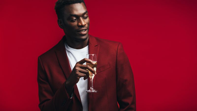 Stylish Black man with a glass of champagne looking away at copy space