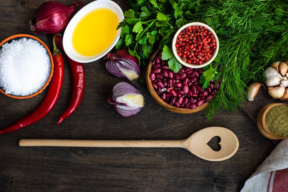 Kitchen counter with seasonings, herbs, chili and dried beans and wooden spoon