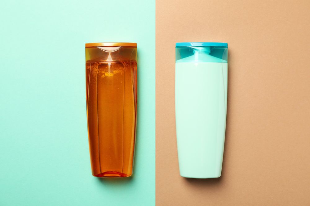 Blank bottles of shampoo on two tone background, space for text
