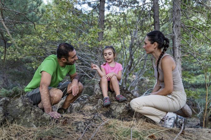 Little girl explaining something to parents during forest walk sharing thoughtful moment