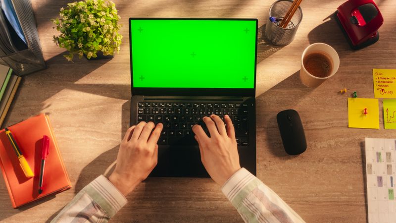 Anonymous Project Manager Typing on a Laptop Computer with Mock Up Green Screen Chromakey Display with Motion Tracker Placeholders. Office Employee Corresponding with Work Partners. Top Down View