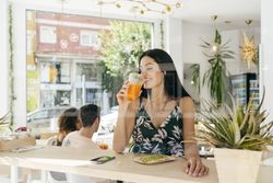 Woman with healthy drink listening to music in cafe