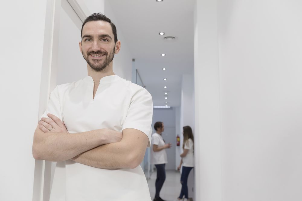 Portrait of confident doctor or dentist standing at the medical office with staff talking in corridor