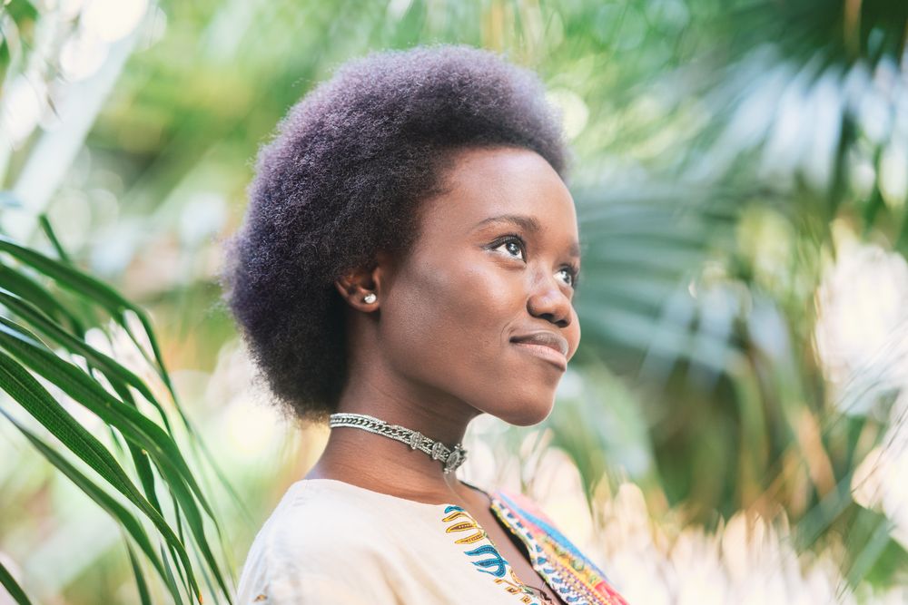 Cheerful Black woman amidst palm leaves