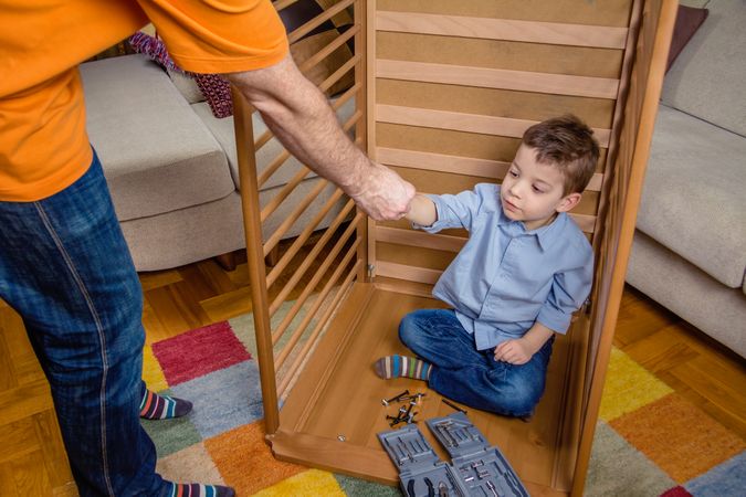 Son and father assembling cot for a newborn at home