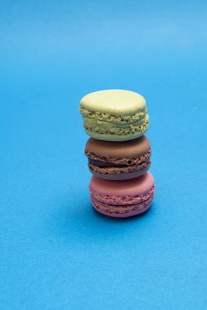Three French pastel macaroons on a blue table