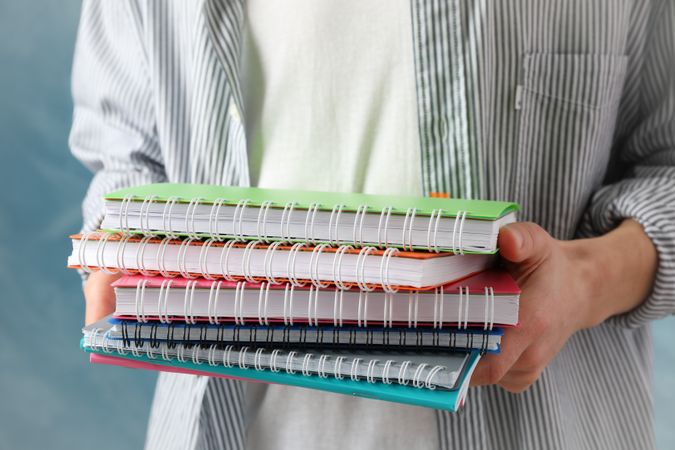 Male holding pile of notebooks