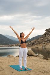 Woman practicing yoga outdoors near water
