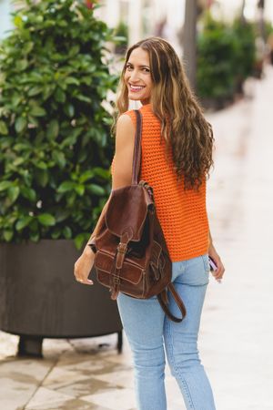 Woman in orange shirt looking behind her outside