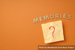 The word “Memories” written in cork on dusty orange background with post it note, copy space 5ag9Ab