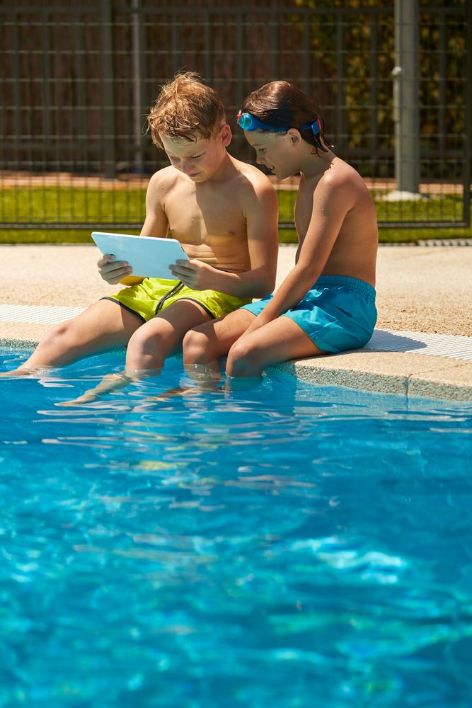 Boys on poolside browsing tablet