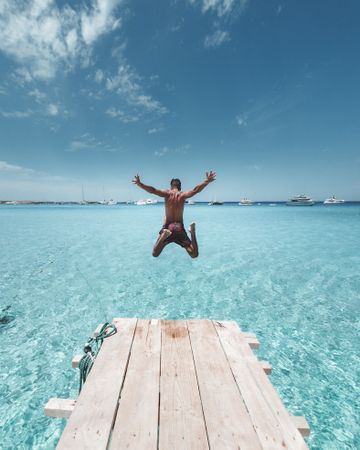 Back view of man jumping on sea water