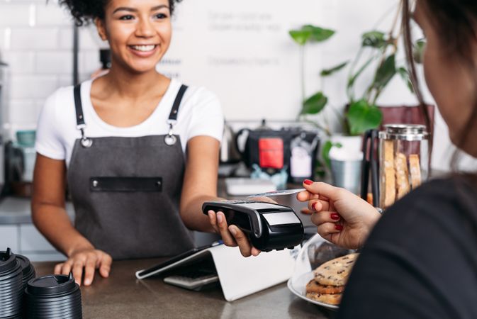 Customer paying barista with credit card in cafe