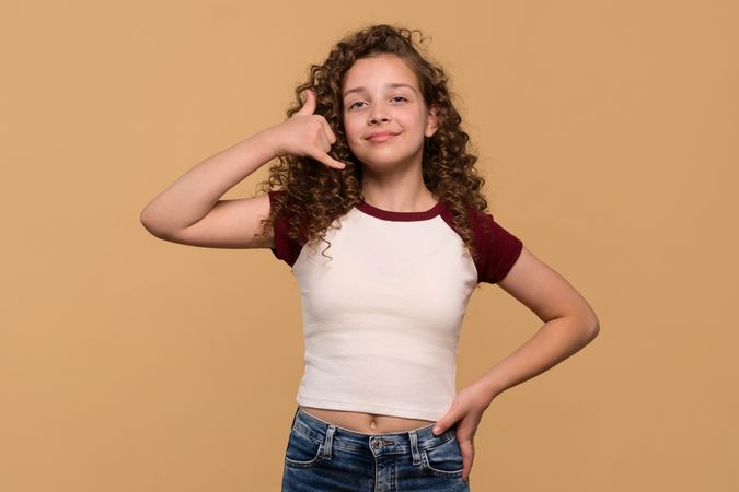 Girl posing with hand gesture call me sign