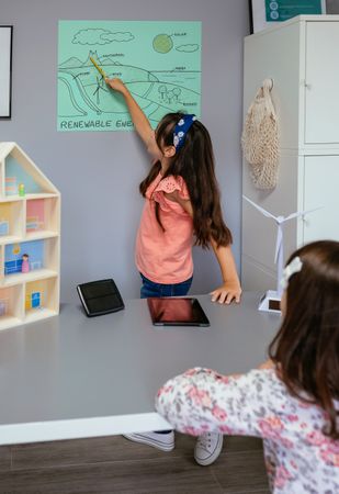 Student showing types of renewable energies in poster at ecology classroom