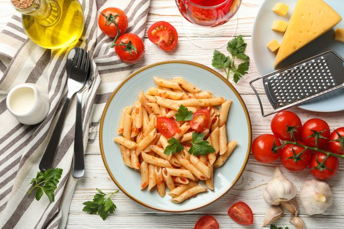 Composition with plate of tasty pasta and ingredients for cooking on wooden background