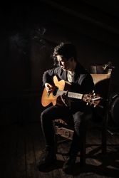 Man with guitar and cigarette sitting on chairs