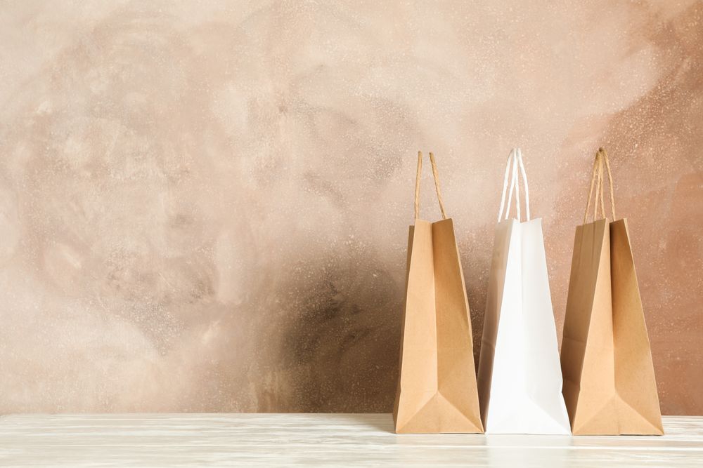 Paper bags on table against brown background, copy space