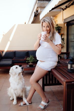 Pregnant woman having breakfast with dog