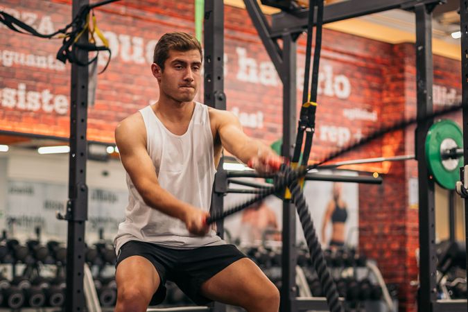 man athlete working out with the ropes in a gym