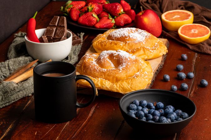 Fresh fruits near bun and hot drink