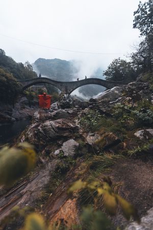 Person holding red textile standing near bridges in Switzerland's natural landscape