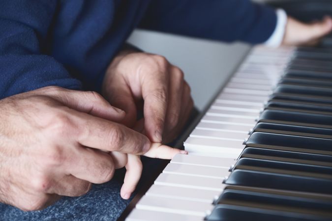 Anonymous father teaching son to play piano