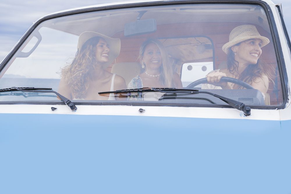 Smiling girlfriends discussing route looking at map in car