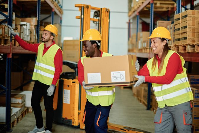 Positive diverse workers unloading boxes in warehouse