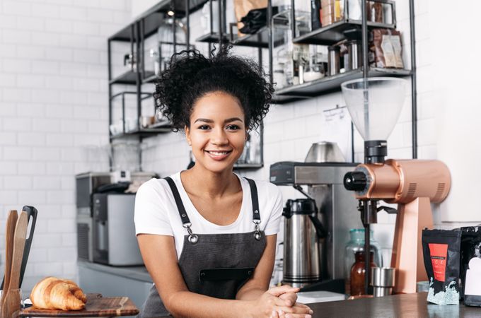 Proud barista leaning on the counter of cafe