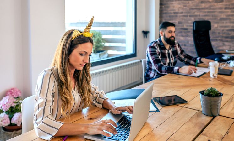 Businesswoman with unicorn headband working while her partner looks at her
