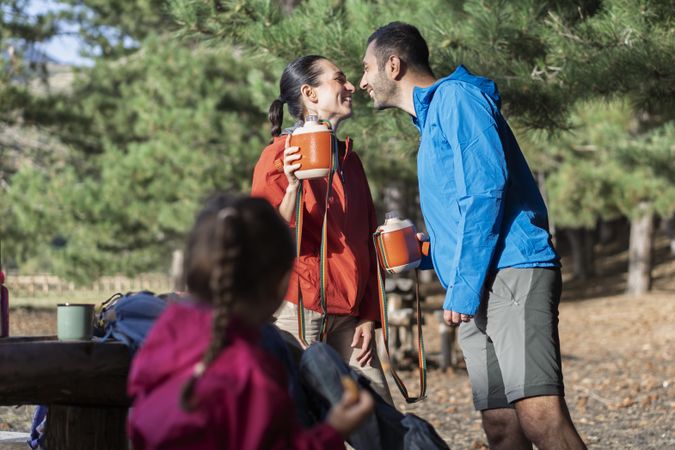Loving couple sharing a kiss during outdoor hike with child in the forest