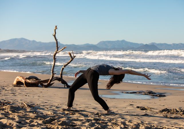 Young woman dancing and posing near water on shore