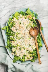 Artichoke salad with wooden serving spoons on marble background