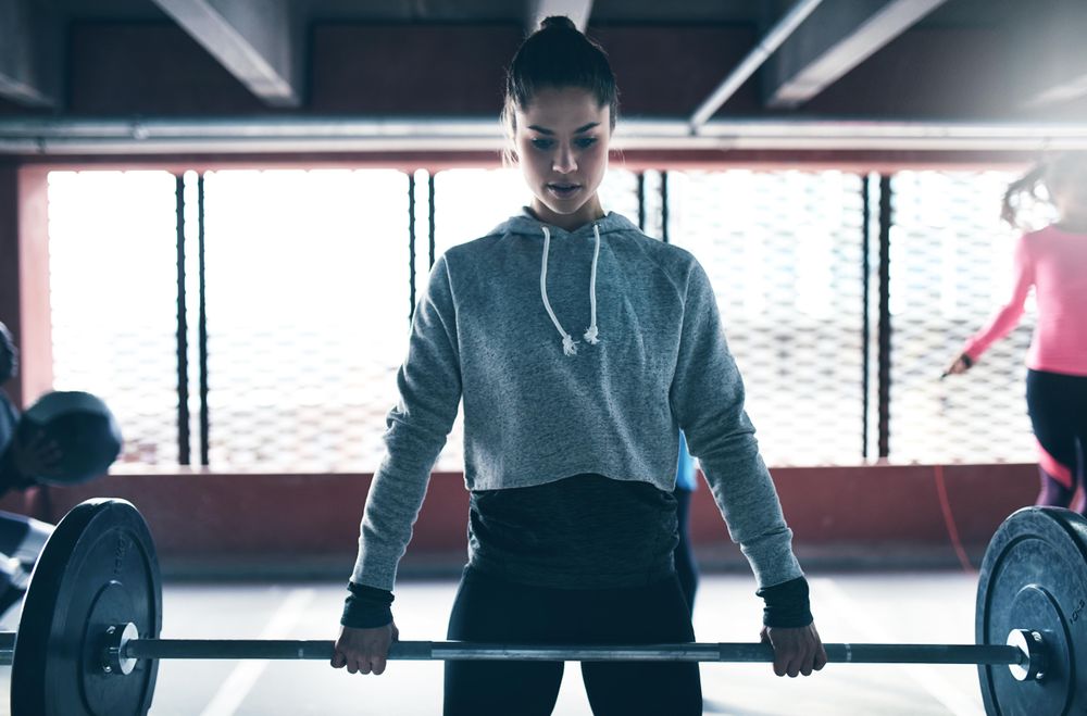 Woman looking down as she holds heavy barbell